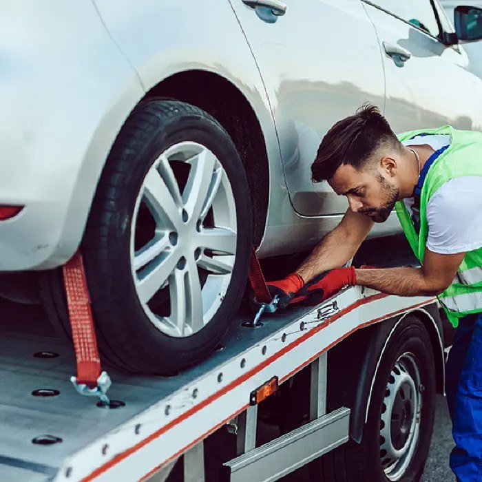 Chicago car shipping services - worker safely strapping down vehicle for transport